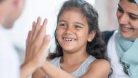 A young girl and her mother giving a doctor a high five